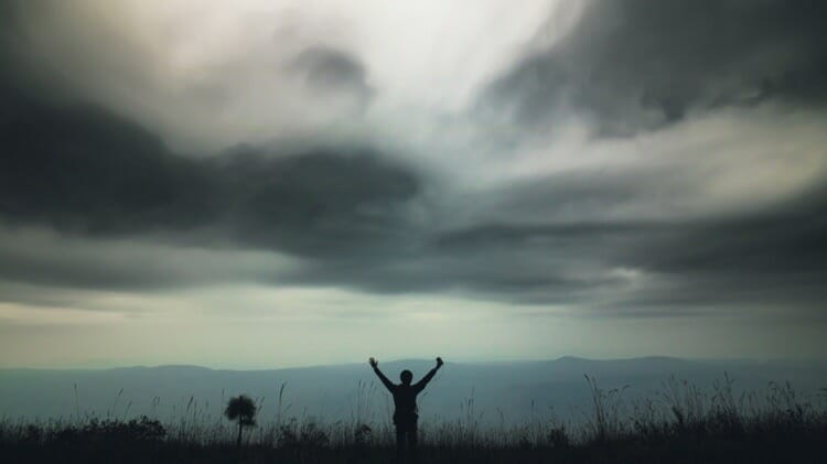 silhouette alone man standing tall grass mountain view with cloudy sky nature cropped 49